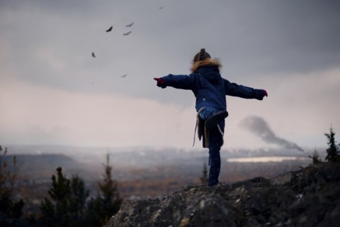 Caucasian girl balancing on rocks imitating flying birds