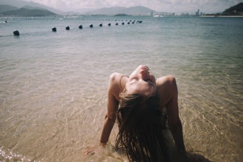 Caucasian woman wearing bikini sitting in waves on beach