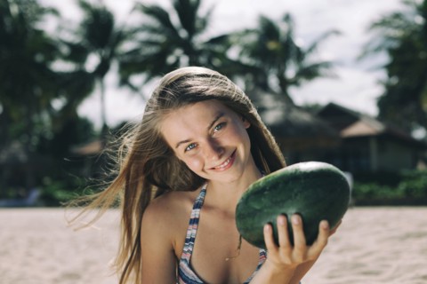 Caucasian woman holding watermelon on beach