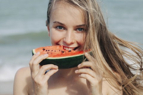 Caucasian woman eating watermelon on beach