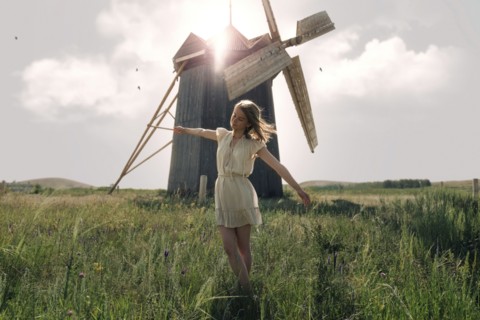 Caucasian woman balancing in grass near windmill