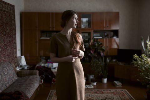 Pensive Caucasian woman standing in livingroom