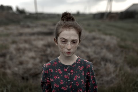 Caucasian girl with freckles raising eyebrow in field
