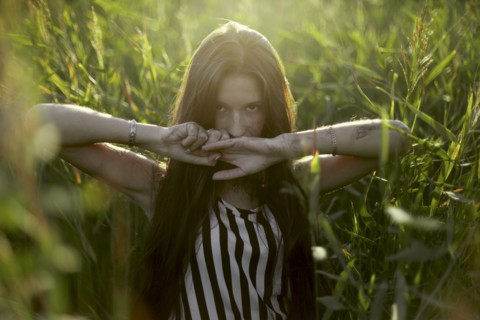 Caucasian woman covering mouth with hands in field