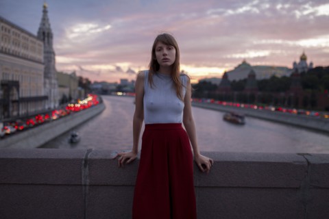 Caucasian woman leaning on bridge over urban canal