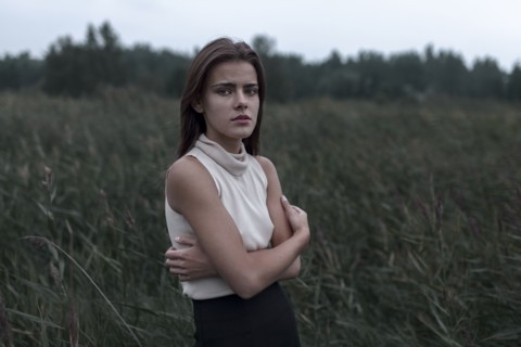 Caucasian teenage girl standing in field worrying