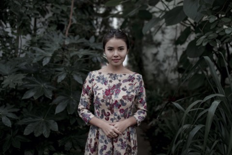 Asian woman smiling near foliage