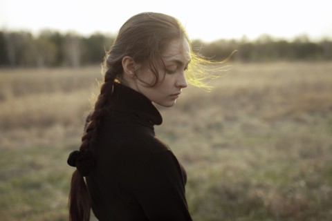 Pensive Caucasian woman standing in field