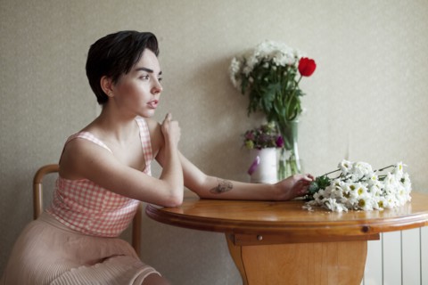 Pensive Caucasian woman sitting at table with flowers