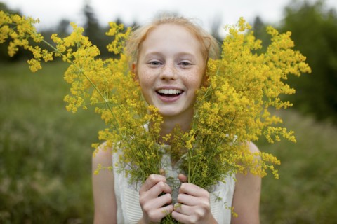 Portrait of smiling Caucasian girl with freckles holding wildflowers