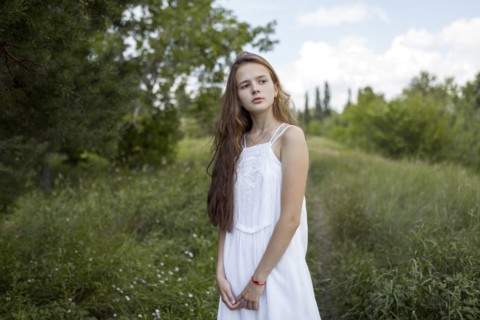 Pensive Caucasian girl standing in field