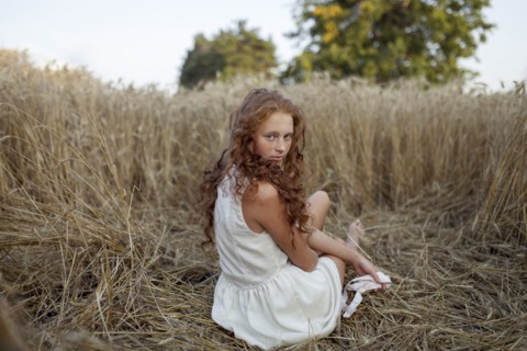 Caucasian girl sitting in wheat