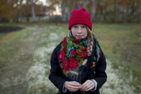 Portrait of Caucasian woman wearing scarf and stocking-cap holding hay seed
