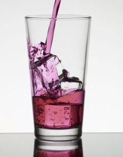 Pink liquid filling glass with ice