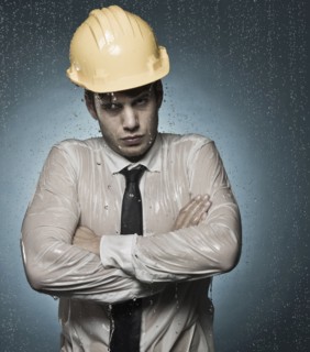 Caucasian businessman in hard-hat standing in rain