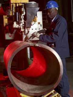 Worker working on steel pipe in factory