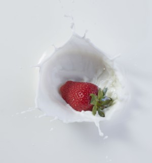 Strawberry dropping into milk