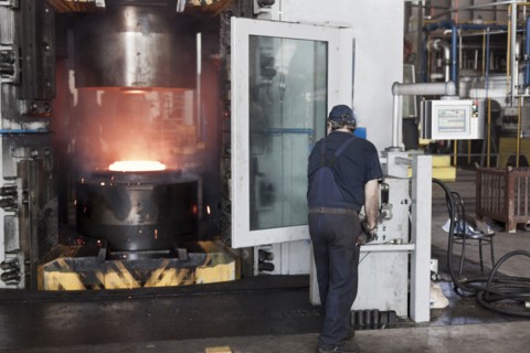 Caucasian worker operating steel melting machinery in factory