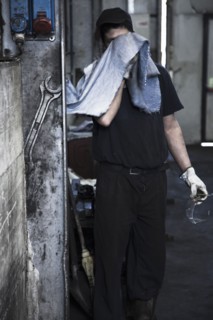 Caucasian worker wiping his face in factory