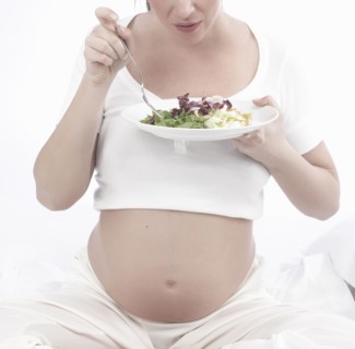 Pregnant Caucasian woman eating salad