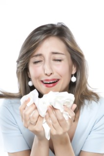 Woman sneezing into tissues