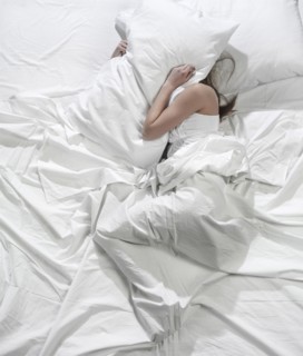 Hispanic woman burying head under pillow