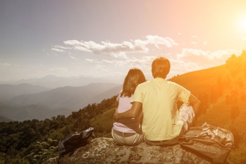 Couple sitting on rock admiring scenic view of mountain