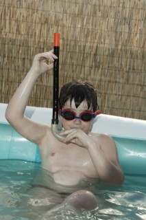 Caucasian boy wearing snorkel in inflatable swimming pool