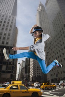 Caucasian man jumping over taxis in city