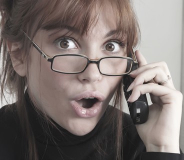 Surprised Caucasian businesswoman talking on telephone