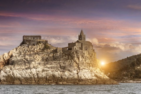 Castle on rock near river at sunset