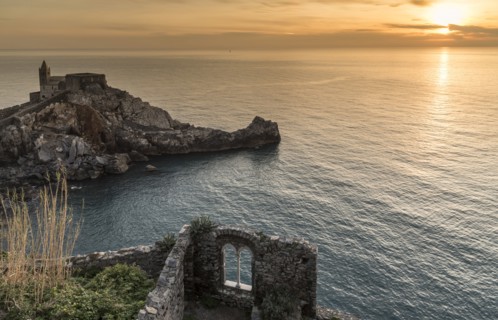 Stone building near ocean at sunset