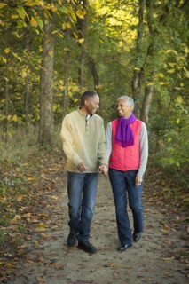 Older couple holding hands walking in forest