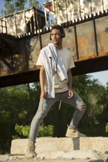 Mixed Race man with shirt draped over shoulders listening to headphones