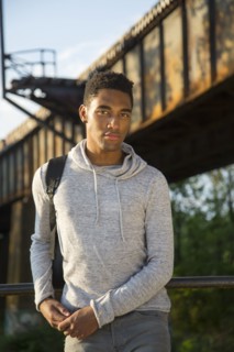 Mixed Race man with backpack leaning on urban railing