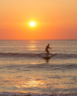 Silhouette of man paddleboarding on ocean waves