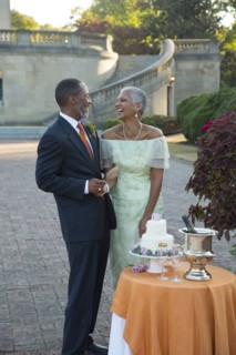Black couple laughing near wedding cake