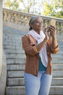 Black woman on stone staircase texting on cell phone