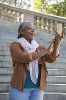 Black woman posing for cell phone selfie on stone staircase