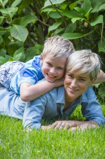 Caucasian boy laying on back of mother in grass