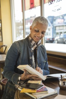 Mixed Race woman reading travel guidebook in coffee shop