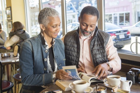 Mixed Race couple reading travel guidebook in coffee shop