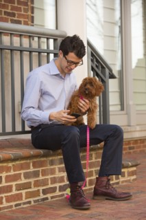 Caucasian man holding dog and texting on cell phone