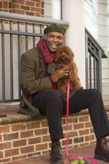 Portrait of African American man sitting on stoop holding dog