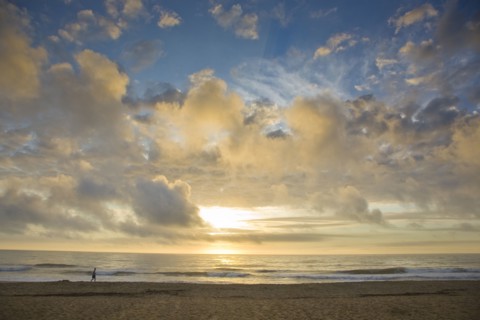 Distant man walking on beach at sunset