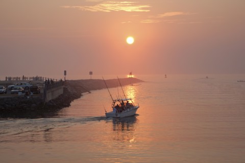 People on boat and at waterfront at sunset