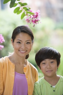 Portrait of smiling Asian mother and son near flowers