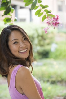 Portrait of smiling Asian woman outdoors near flowers