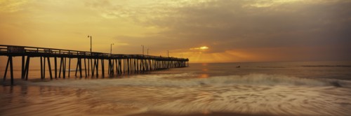 Ocean waves under pier at sunset