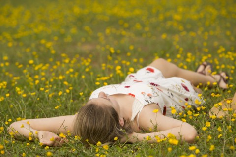Caucasian teenage girl laying in field of flowers